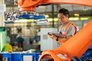 Skilled manufacturing technician using custom automation solutions to monitor multiple production lines, demonstrating workforce amplification.